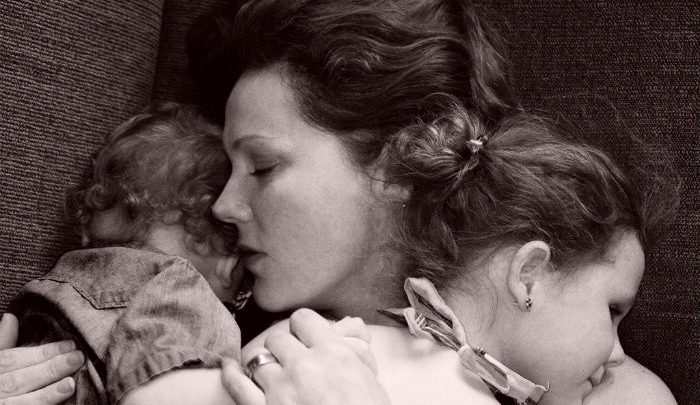 Sleeping mother holding two sleeping childeren