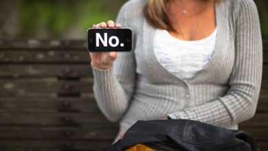 Woman holding her phone out with the word NO typed out on it