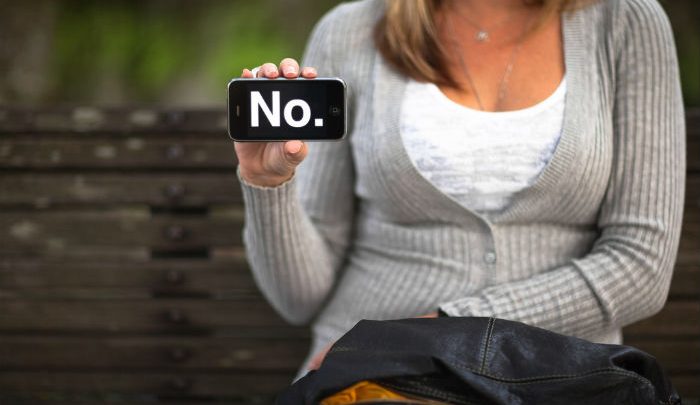Woman holding her phone out with the word NO typed out on it