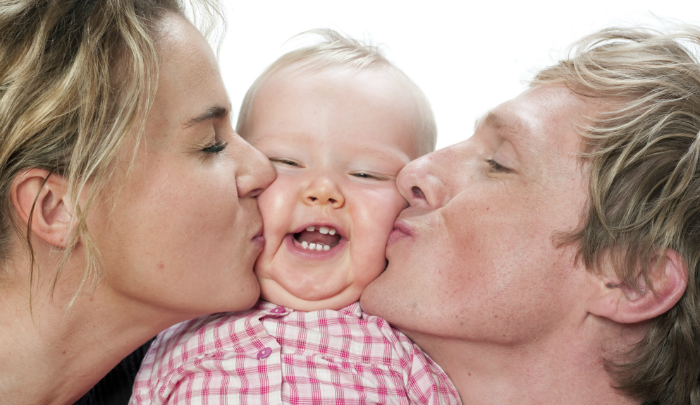 Mom and Dad kissing a babies cheeks