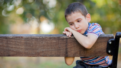 boy sitting on a wooden bench looking sad: parents, are you there but not really there?