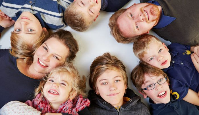 Happy family lying on the floor in a circle smiling up at the camera