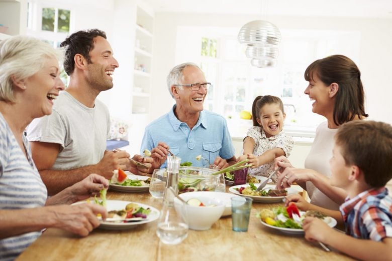 Grandparents, Parents, and Children sitting around the dinner table having a happy family meal