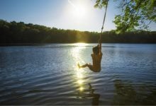 Boy on a rope swing over a lake