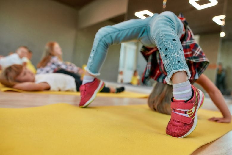 Child doing a backbend on a yoga mat